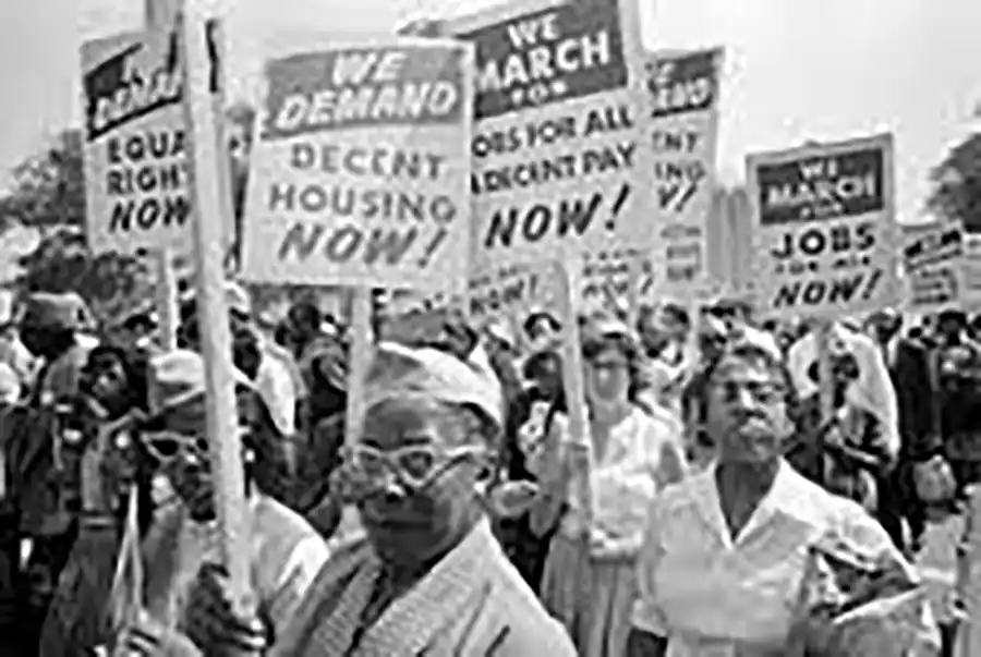 An group of African American women marching with signs, in what appears to be the 1950s. The signs read: "We demand decent housing now!" and "We demand equal rights now!" and others about jobs and pay.