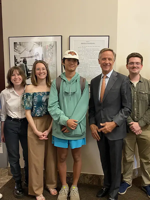 Four students post for a photo with Bill Haslam