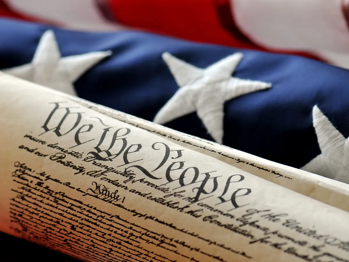 The US Constitution is pictured against an American flag.